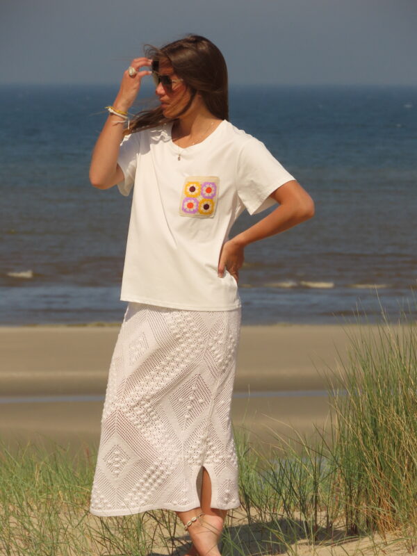 Tee-shirt blanc à manches courtes avec poche décorative florale en macramé sur le côté cœur.