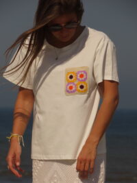 Tee-shirt blanc à manches courtes avec poche décorative florale en macramé sur le côté cœur.