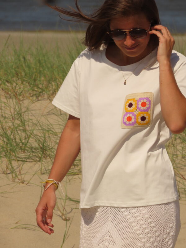 Tee-shirt blanc à manches courtes avec poche décorative florale en macramé sur le côté cœur.