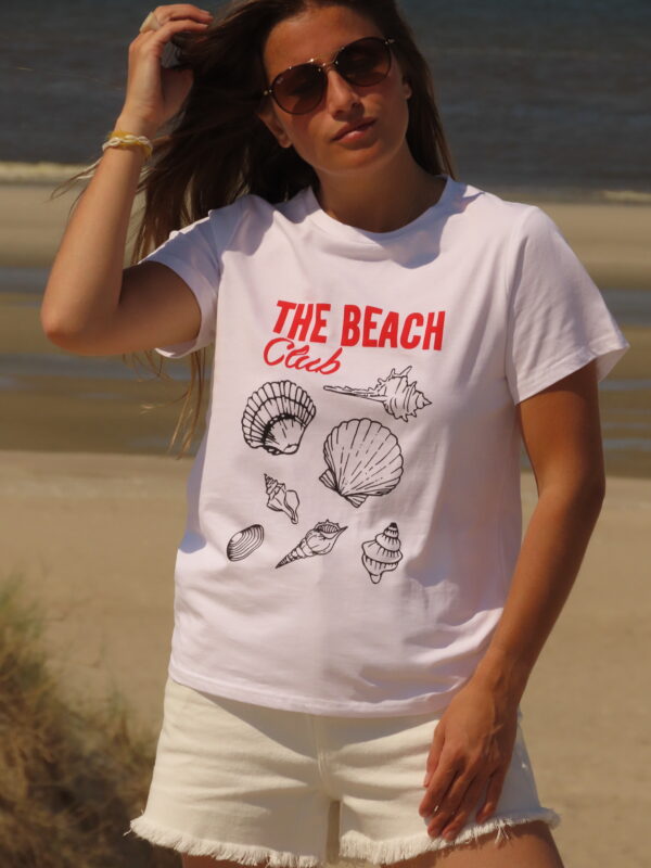 Tee-shirt blanc 100% coton, manches courtes, imprimé "Beach Club" en rouge avec motifs de coquillages noirs.