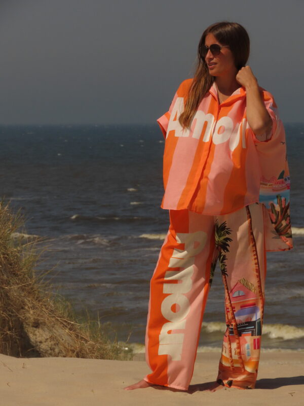 Pantalon Amour ample avec élastique à la taille, imprimé "Amour" sur une jambe et motif bord de mer sur l'autre, rayures roses et oranges