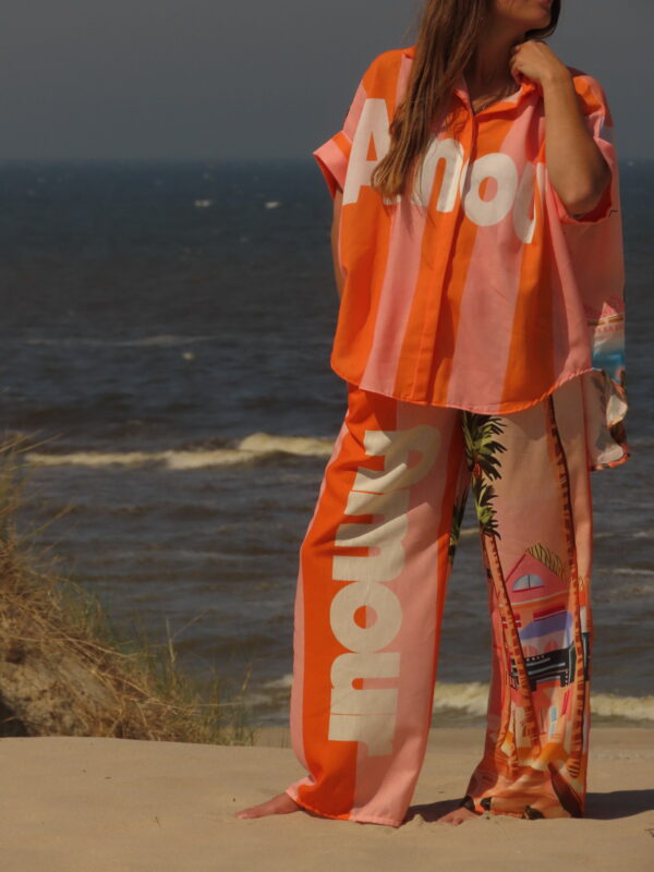 Pantalon Amour ample avec élastique à la taille, imprimé "Amour" sur une jambe et motif bord de mer sur l'autre, rayures roses et oranges