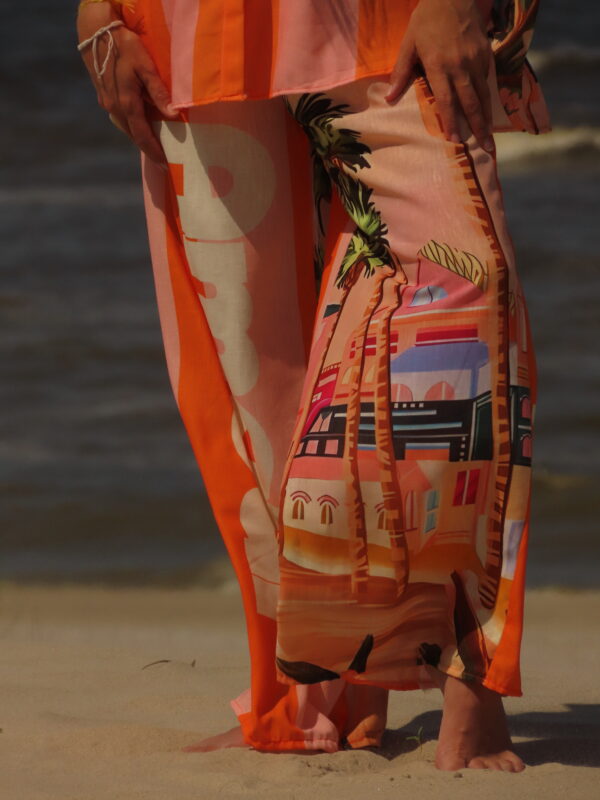Pantalon Amour ample avec élastique à la taille, imprimé "Amour" sur une jambe et motif bord de mer sur l'autre, rayures roses et oranges
