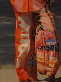 Pantalon Amour ample avec élastique à la taille, imprimé "Amour" sur une jambe et motif bord de mer sur l'autre, rayures roses et oranges