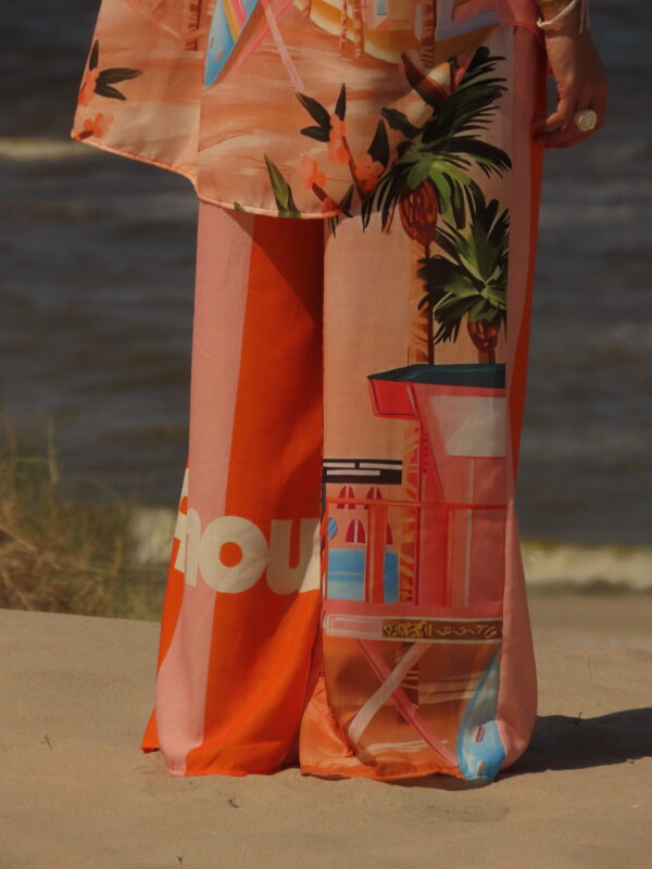 Pantalon Amour ample avec élastique à la taille, imprimé "Amour" sur une jambe et motif bord de mer sur l'autre, rayures roses et oranges