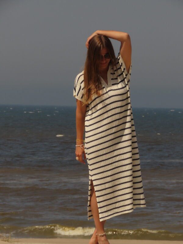 Robe Riviera longue à rayures bleues et blanches avec fente en bas, portée en extérieur lors d'une journée ensoleillée.