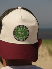 Casquette trucker blanche avec visière kaki et filet bordeaux, ornée d'un écusson Sea View brodé sur le devant.