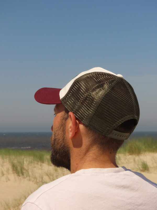Casquette trucker blanche avec visière kaki et filet bordeaux, ornée d'un écusson Sea View brodé sur le devant.