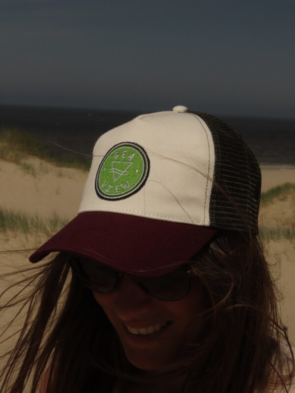 Casquette trucker blanche avec visière kaki et filet bordeaux, ornée d'un écusson Sea View brodé sur le devant.